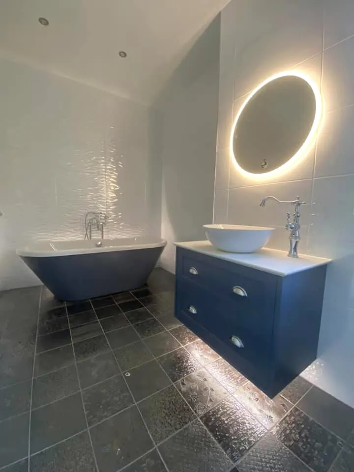 Freestanding bath beside a navy vanity